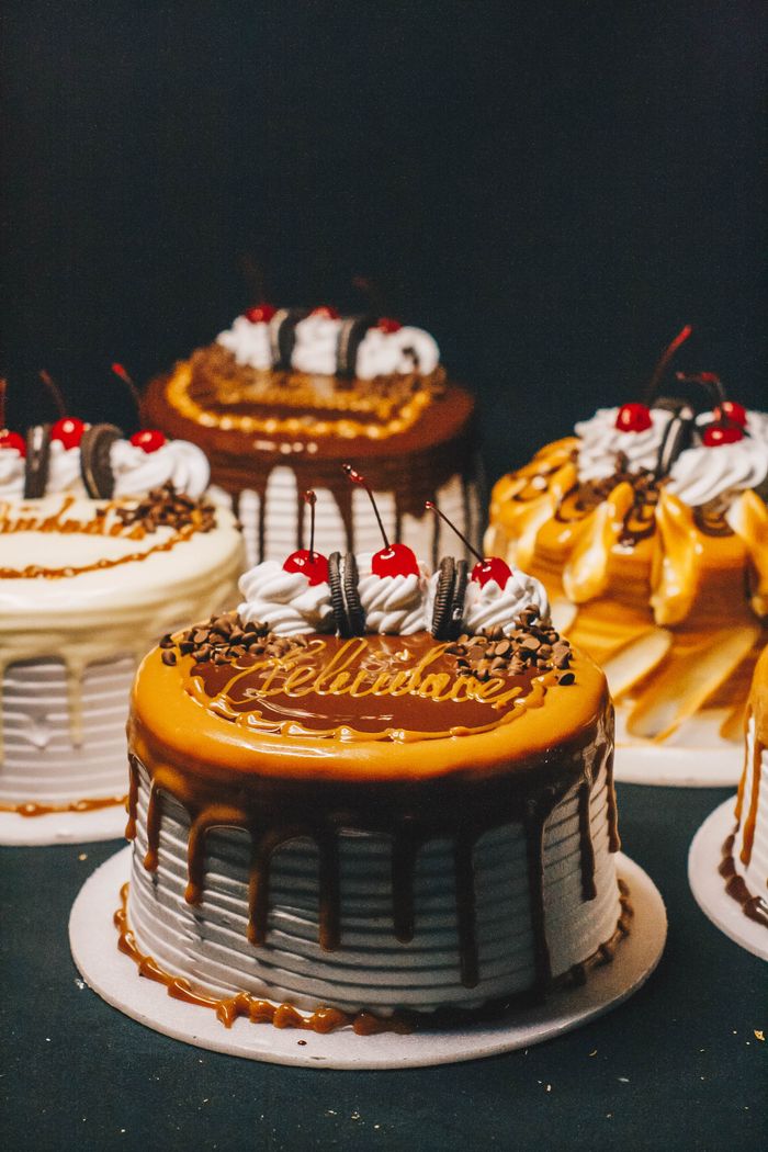 A mouthwatering variety of drip cakes perfect for birthdays or celebrations, adorned with cherries and chocolate.