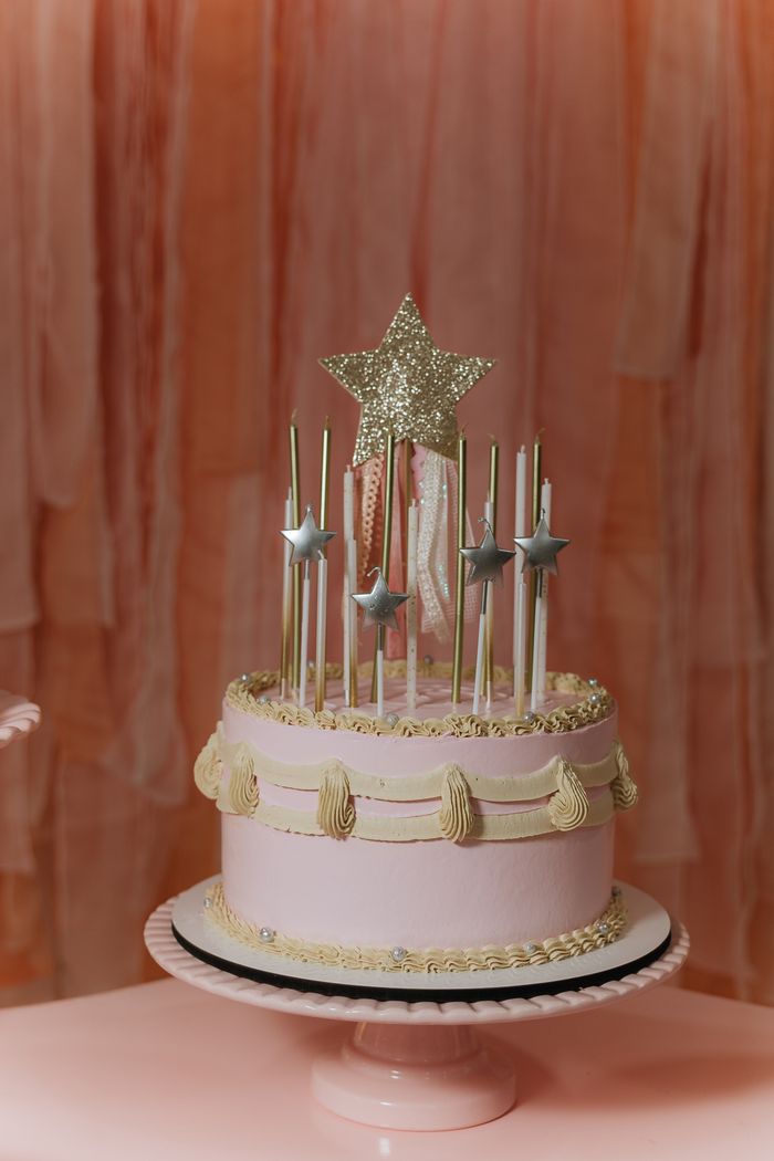 A beautifully decorated pink birthday cake with stars and gold accents, perfect for celebrations.